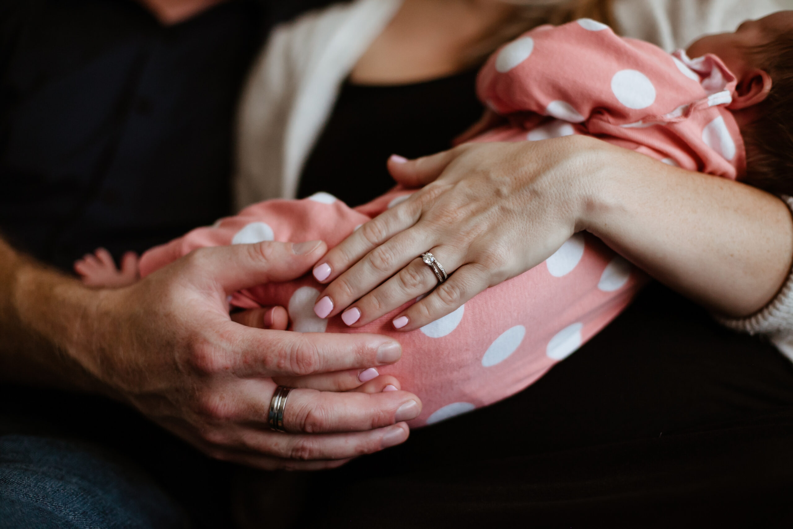 Father and Mother's hands hold newborn baby